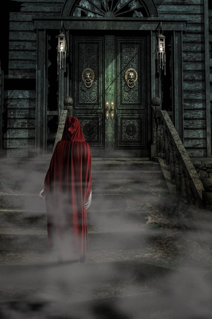 Une femme avec une cape rouge devant une porte de manoir