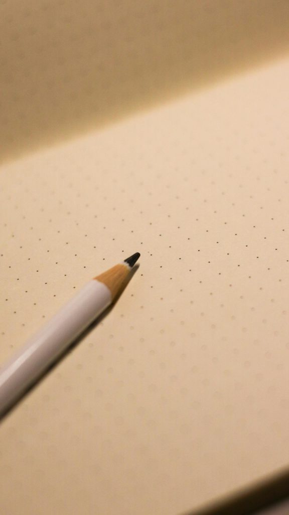 A close-up of a pencil resting on an open dotted notebook page, perfect for business or education themes.